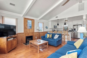Ein geräumiges Wohnzimmer mit einem blauen Sofa, einer Holz-Unterhaltungseinrichtung und einem Flachbildfernseher.