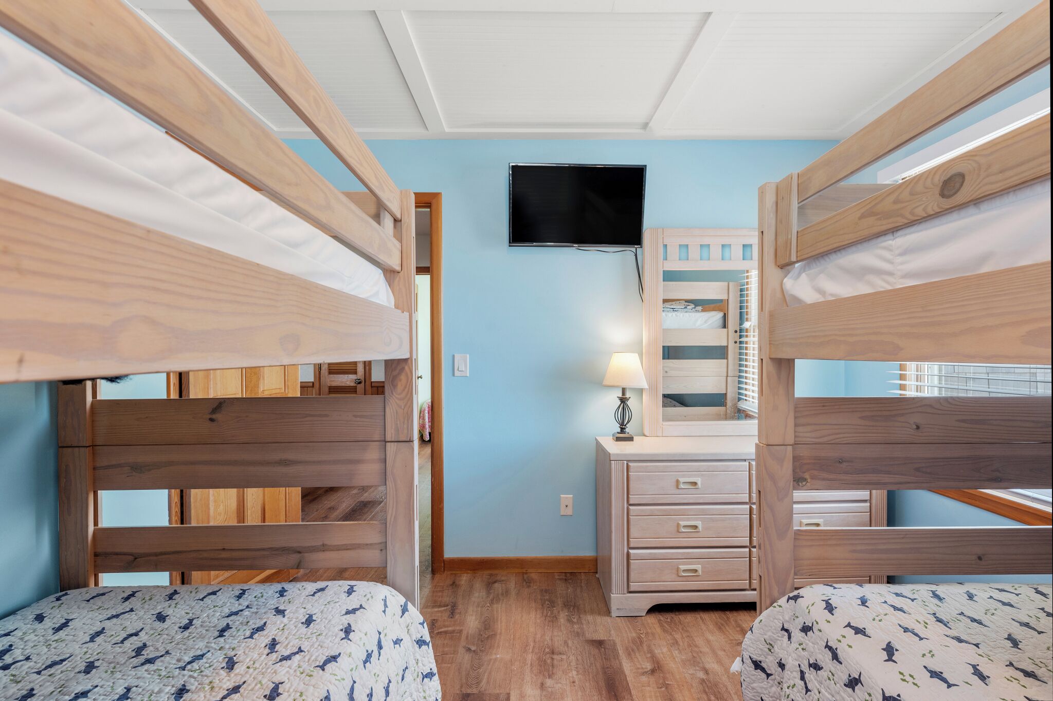 A bedroom with bunk beds, a flat-screen TV, a dresser, and a mirror.