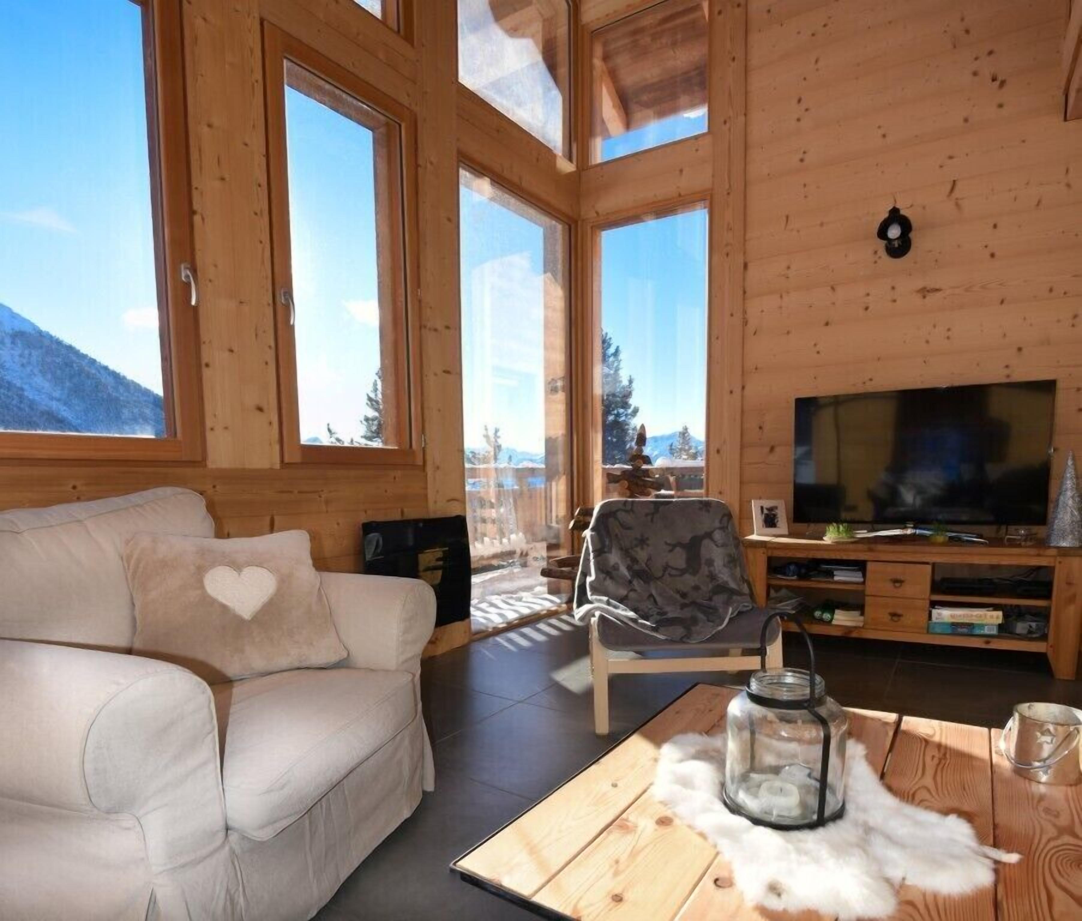 L’intérieur d’un chalet accueillant, avec un canapé, un téléviseur et une table en bois.