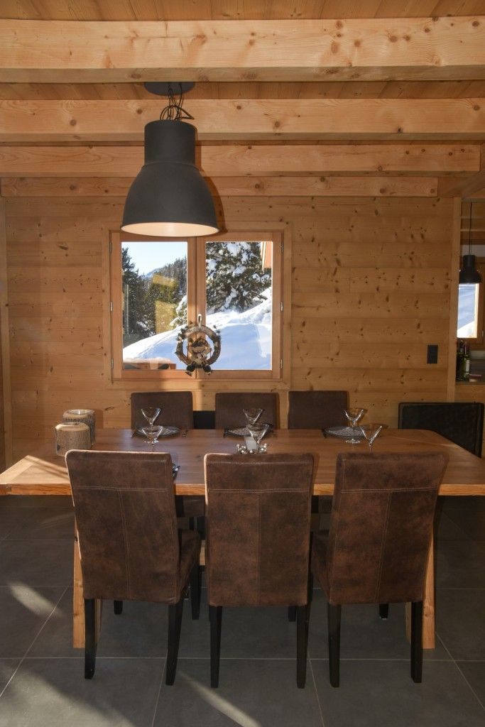 A wooden dining area with a table set for four, a pendant light, and a window with a snowy view.