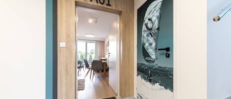 A hallway with a wooden door labeled "A01" leading to a dining area with chairs and a table.