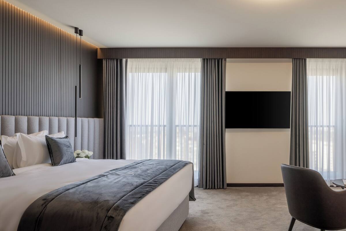 A modern hotel room with a large bed, a flat-screen TV, and a seating area.