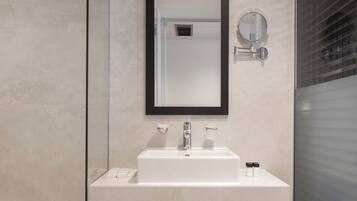 A modern bathroom with a glass shower enclosure, a white sink with a black countertop, and a large mirror with a black frame.