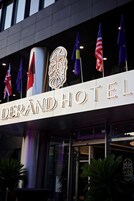 El exterior del Hotel Derand, con su nombre bien visible. Se observan banderas de varios países, entre ellos Reino Unido, Alemania y Estados Unidos.