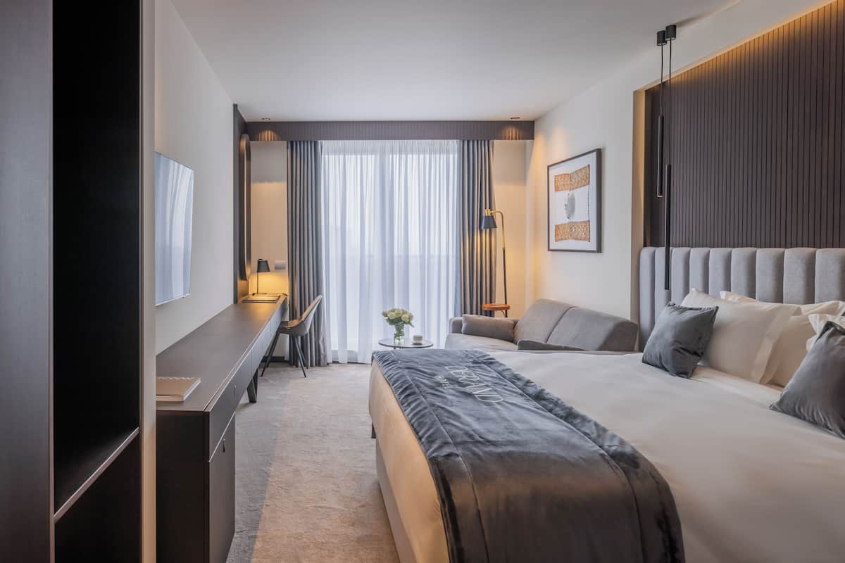 A modern hotel room with a large bed, a desk, and a chair.