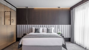 A modern bedroom with a large bed, a headboard with vertical lines, and a large window with curtains. - Derand Hotel (Pristina)