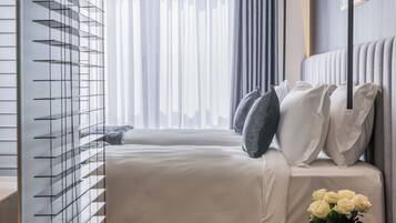 Una habitación de hotel moderna con una cama grande, una mesita de noche con un florero y vistas a la ciudad a través de la ventana.