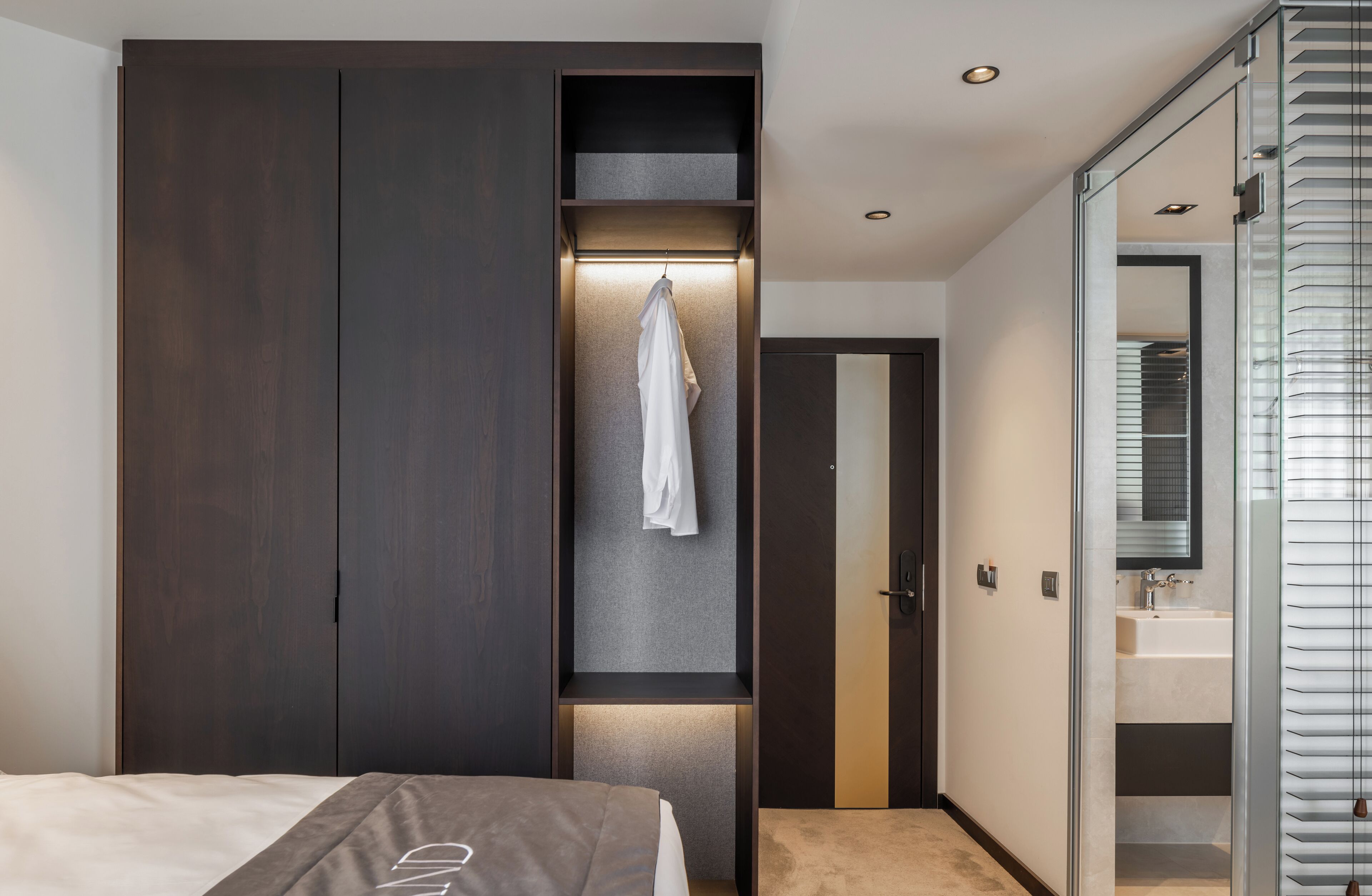 Een moderne slaapkamer met een grote garderobe, een kapstok en een douchecabine met glazen wanden.