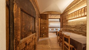A narrow hallway with wooden walls and a table set for dining. - Casa Aquila, with sauna and Turkish bath (Cortina d´Ampezzo)