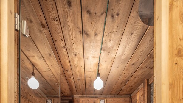 A sauna with wooden walls and a tiled floor, featuring a bench, a bucket, and a towel rack. - Casa Aquila, with sauna and Turkish bath (Cortina d´Ampezzo)