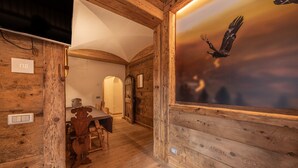 A wooden interior with a dining area, a wall-mounted TV, and a large window with a bird mural. - Casa Aquila, with sauna and Turkish bath (Cortina d´Ampezzo)