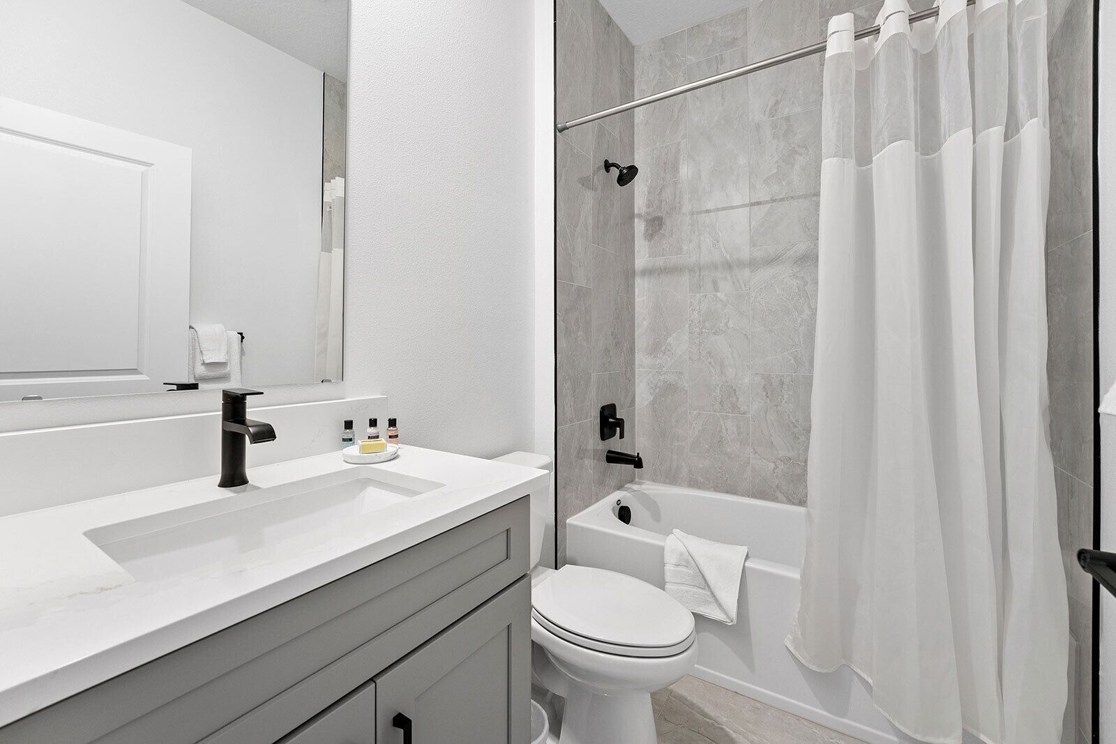A modern bathroom with a white sink, a toilet, a bathtub, and a shower.