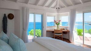 Een slaapkamer met een groot bed, een bureau en uitzicht op zee.