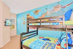 Een kinderkamer met stapelbedden, een muurschildering van zeedieren en een televisie aan de muur.