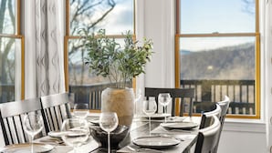 A dining table set with plates, glasses, and a vase with plants. - Stunning Views, Hot Tub, Impeccable Design (Wintergreen Resort)