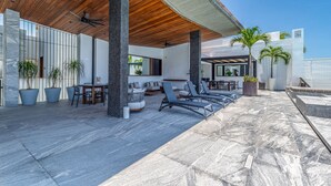 Eine moderne Lounge-Bereich im Freien mit Sitzgelegenheiten, einem Pool und einer überdachten Terrasse.