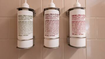 Three toiletry bottles mounted on a wall with a chrome faucet below.