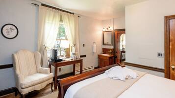 A hotel room with a bed, a chair, a table with a lamp, a sink, and a mirror.