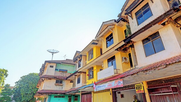 A multi-story building with various shops on the ground floor, including a visible sign for a laundry service.