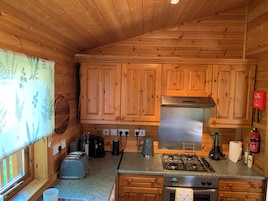 A wooden cabin kitchen with a gas stove, oven, and a coffee maker.