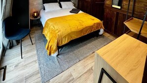 A modern bedroom with a bed, bedside table, chair, and a wooden desk.