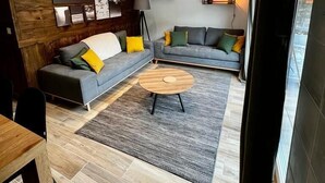 A modern living room with a grey sofa, a wooden coffee table, and a grey rug.