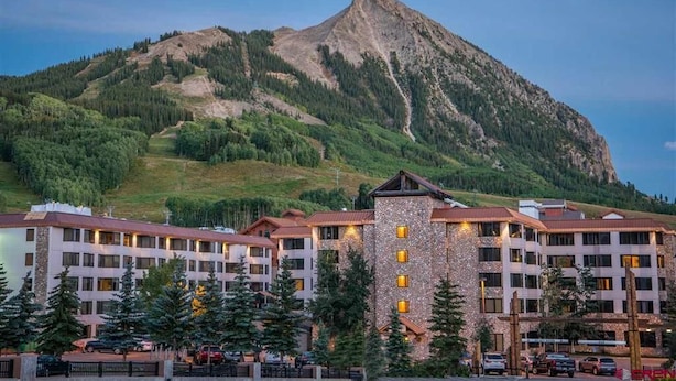 Un hôtel à étages, doté d’une tour centrale et situé au pied d’une montagne.