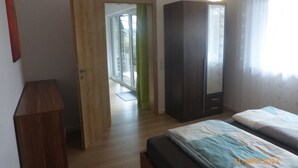 A bedroom with a bed, a wardrobe, and a door leading to a balcony. - Ferienwohnung Lehrberg - Moderne Wohnung mit Wallbox für E-auto (Lehrberg)