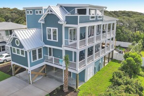 A multi-story house with a balcony, a garage, and a well-maintained lawn.