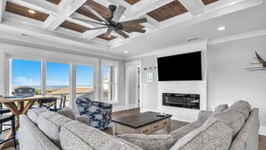 A modern living room with a sectional sofa, a coffee table, and a TV mounted on the wall. - Fanta Sea: Modern Home Built in 2023 with Private Pool, Elevator (Oak Island)