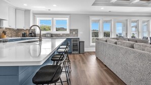 A modern kitchen with a large island, bar stools, and a built-in oven. - Fanta Sea: Modern Home Built in 2023 with Private Pool, Elevator (Oak Island)