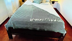 A bed with a patterned bedspread, two bedside lamps, and a wall-mounted picture. - Apartamentos El Labrador # 10 (Tamarindo)