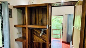 A room with a wooden shelving unit, a tiled floor, and a view of greenery outside. - Apartamentos El Labrador # 10 (Tamarindo)