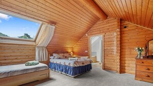 Et hyggeligt soveværelse i en træhytte med seng, bænk og kommode.