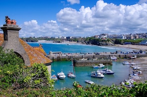 Stroll across the historic stone bridge to the charming harbor, where small boats bob gently in the water.