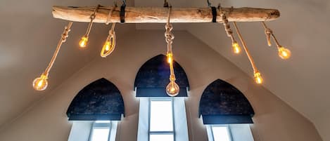 A rustic chandelier with multiple light bulbs hanging from a wooden beam.