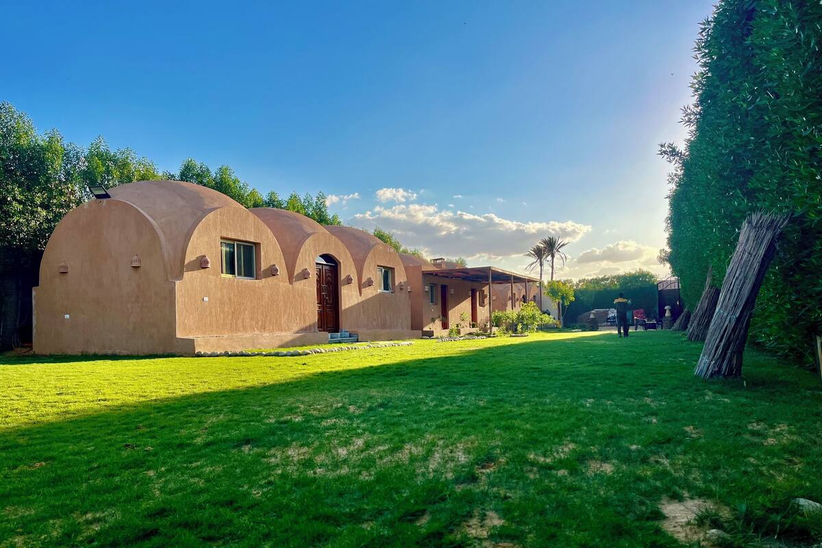 A row of dome-shaped buildings with a grassy lawn in front.