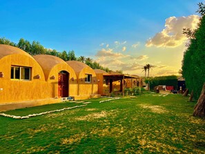 A row of dome-shaped cottages with a grassy lawn and a clear sky. - King Sahure Pyramid Inn (Al-Badrashayn)