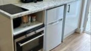 A compact kitchen with a built-in oven, a coffee maker, and a sink. - Perfect stay with Dallas Studio (Hayes)