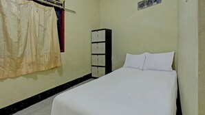 A small, clean room with a single bed, a wardrobe, and a curtain. - Hotel O Penginapan 3 Bersaudara Near Pasar Sengkol (Janapria)