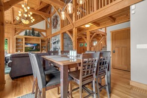 Relax in a spacious room with a high ceiling, exposed beams, and a cozy fireplace.