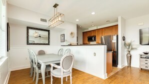 A modern kitchen with wooden cabinets, a central island, and stainless steel appliances. - Dog Friendly Condo; Pointe West Amenities: POOL, hot tubs, walking & bike paths (Galveston)
