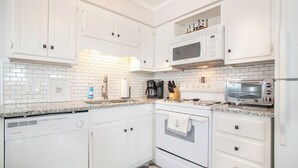 A kitchen with white cabinetry, a built-in microwave, a coffee maker, and a toaster. - Southwinds G16 (Ocean View) (Atlantic Beach)