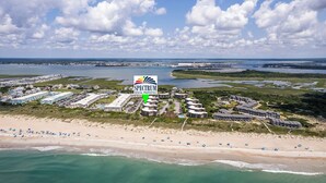 An aerial view of a coastal rental property complex with multiple buildings, a beach, and a marina. - Southwinds G16 (Ocean View) (Atlantic Beach)