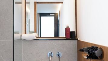 A modern bathroom with a large mirror, a white sink, and a towel rack.