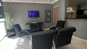 A modern interior with a dining area, a flat-screen TV, and a reception desk. - Renata Palace Hotel (Tubarao)