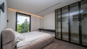 A modern bedroom with a large bed, a wardrobe with glass doors, and a view of greenery outside. - The Villa O, a unique luxury experience in Sarajevo (Sarajevo)