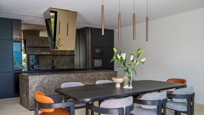 A modern kitchen with a central island, dark-toned dining table, and matching chairs. - The Villa O, a unique luxury experience in Sarajevo (Sarajevo)