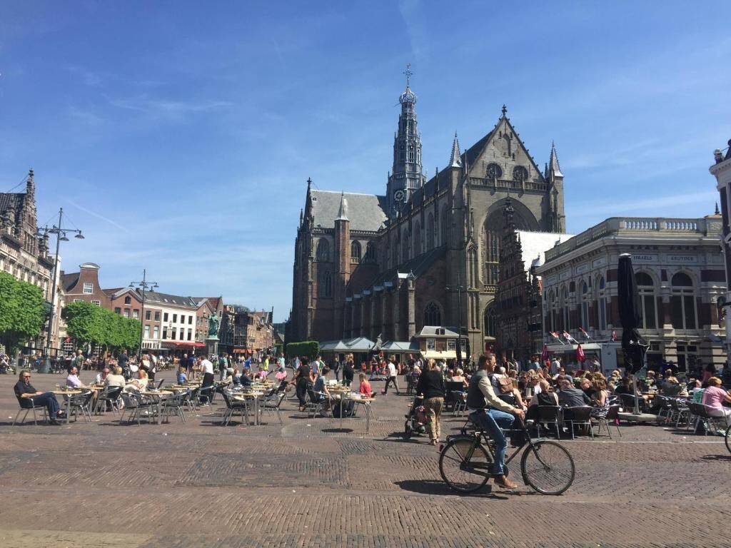 Ein historischer Platz mit einem markanten Kirchengebäude, Außenbereichen zum Verweilen und verschiedenen Gebäuden.