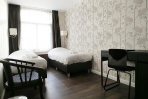 A hotel room with two beds, a desk, and a chair.